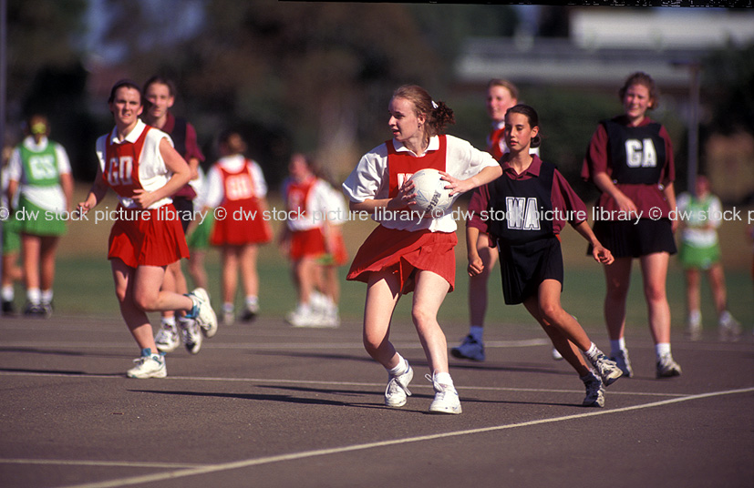 stock photo image: People, child, children, puberty, Australia, New South Wales, Sydney, Female, Females, Girl, girls, Teenager, Teenagers, Teenage girl, Teenage girls, Adolescent, Adolescents, outdoors, Sport pictures, Sports, netball, netball game, netball games, ball game, balls games, ball, balls, uniform, informs.